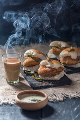 A cup of chai with vada pav served on the table