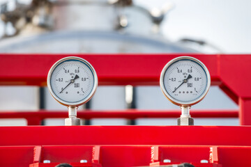 Two white and silver gauges on a red metal frame