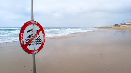 warning sign on the beach indicating a danger current red panel of potential danger in the water