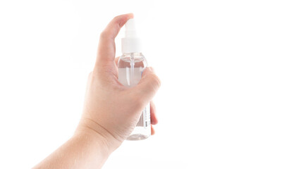Hand spritzing clear liquid from a transparent spray bottle in a bright setting for refreshing or...