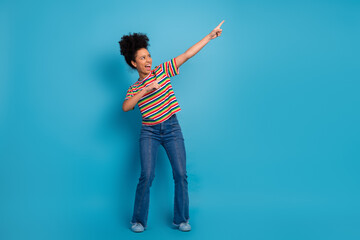 Young woman in striped t-shirt gestures energetically against a turquoise background, expressing...