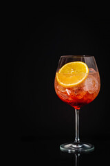 Aperol spritz cocktail in a glass with ice and orange on a black background