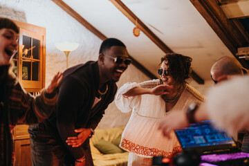 Friends having fun together at a casual indoor party with music and dancing. The space is cozy and...