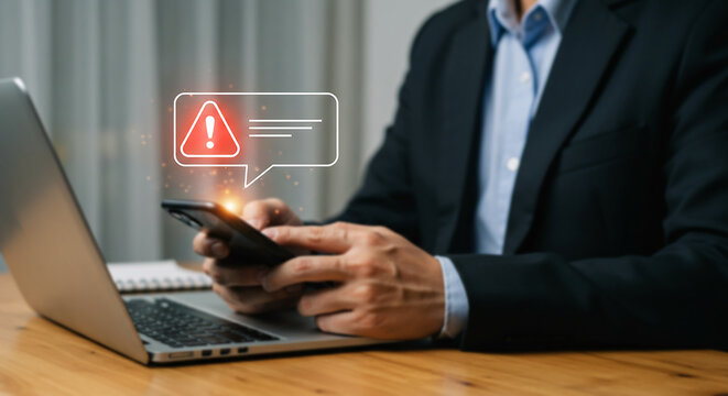 Urgent Smartphone Notification: A businessman receives an urgent notification on his smartphone, a red alert symbol appearing above the message.