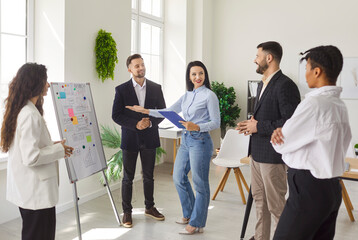 Group of young confident business people standing in a circle in modern office discussing job...