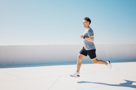 Running towards wellness on a sunlit rooftop in a vibrant urban landscape during a clear blue day