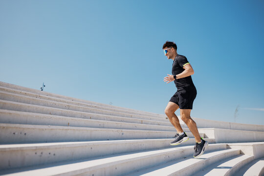 Elevating fitness and determination as a runner conquers modern architectural stairs under a clear blue sky - Powered by Adobe