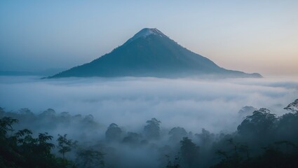 A mountain volcano covered in snow, surrounded by a sea of clouds and forested landscape.