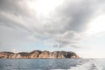 Vast cliffs loom over calm ocean waves, their rugged beauty contrasting against a backdrop of moody...