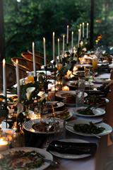 Elegant dinner table setting with candles and gourmet food ready for a celebration in a lush green environment