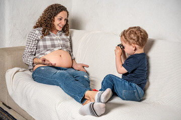 Curious son looking closely with binoculars at his mom’s pregnancy
An infant wants to know what sibling will come out of her mother.