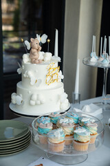 Adorable birthday cake with a teddy bear topper and colorful cupcakes on a dessert table