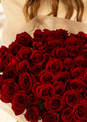 Bouquet of Red Roses Held by Woman in Soft Lighting for Romantic Occasion or Celebration