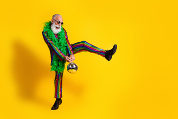 Full size photo of excited old man showman discoball dancing wear glamour striped bright clothes boa sunglass isolated yellow background