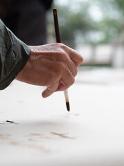 Artist painting with brush on white canvas: ikebana workshop