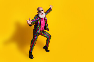 Eccentric elderly gentleman in vibrant suit bursts with energy against bright yellow background