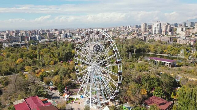 Yerevan, Armenia - 19th october, 2024: Aerial panoramic view ferris wheel in Victory Park ir with cityscape and buildings of Yerevan. Sunny autumn day carousels day out things to do concept