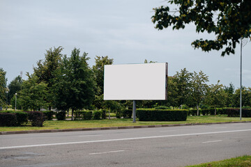 Blank white horizontal billboard against the city background in the daytime. Mockup, advertising...