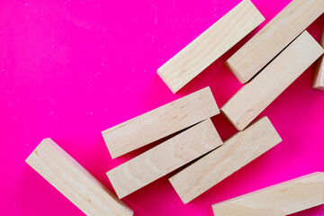 Bright wooden blocks, haphazardly scattered across a saturated fuchsia background, create an appealing and dynamic composition.