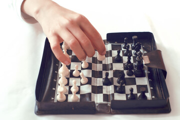 Child hand´s  playing chess game on a small magnetic chessboard
