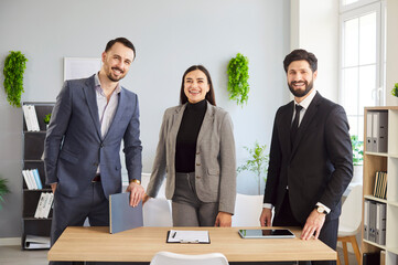 Friendly office workplace environment, two men and one woman smiling, group portrait of colleagues...