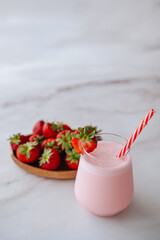 Glasses of fresh strawberry smoothie on a grey background. Summer drink shake, milkshake and...