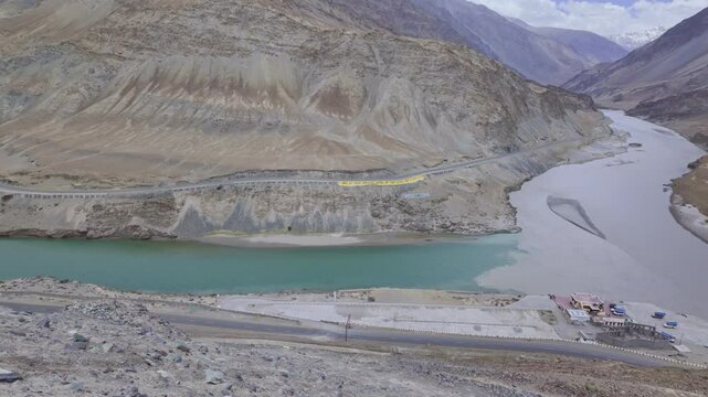  Sangam Point is The confluence of the Indus and Zanskar rivers has two different colors of water between Kargil and Leh, India. landscape with a  river winding through a deep valley.