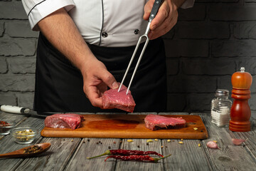 A chef is skillfully handling a piece of raw meat with a fork, surrounded by spices and ingredients on a wooden board in a rustic kitchen setting at night