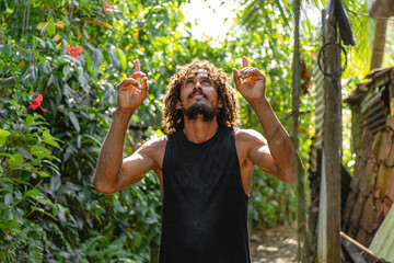 Man pointing upwards with both hands in a lush tropical setting