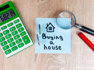 Buying a House text,writing a note on a piece of paper with a calculator drawing of a house,renting a house,real estate,buying,real estate services,affordable housing.