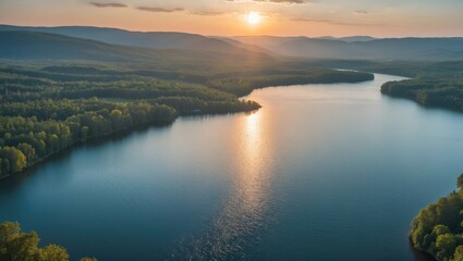 Fototapeta premium Sunset over a river with forested banks and distant mountains.