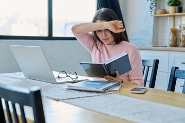 Middle aged sad stressed woman sitting at home office at table with computer