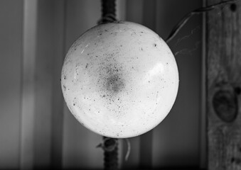 A perfectly spherical, pale white orb hangs suspended, its subtle textures contrasting against the blurred, industrial backdrop of corrugated metal and warm wood.