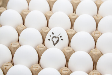 white chicken eggs in the cardboard egg tray with a drawing of heart