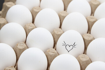 white chicken eggs in the cardboard egg tray with a drawing of heart