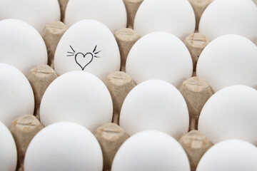 white chicken eggs in the cardboard egg tray with a drawing of heart