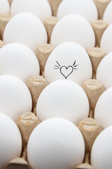 white chicken eggs in the cardboard egg tray with a drawing of heart