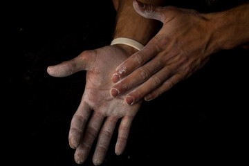 Close-up of a shirtless muscular man rubbing chalk on his hands before training or climbing. The...