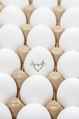 white chicken eggs in the cardboard egg tray with a drawing of heart
