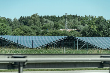 Solar panels installed in a green field near a highway during daytime in a rural area