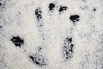 White rice grains with black background whit a hand mark