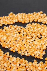 Yellow corn grains with a black background forming a heart drawing