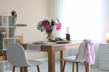 Beautiful table setting with bouquet of peonies in dining room. Interior design