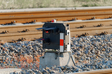 Railway signal system positioned next to railway tracks on a clear day in a rural area