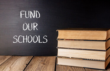 Stack of books with the words fund Our Schools written on a chalkboard