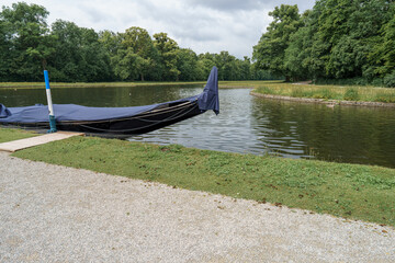 Peaceful gondola at a serene lake surrounded by lush greenery on a cloudy afternoon