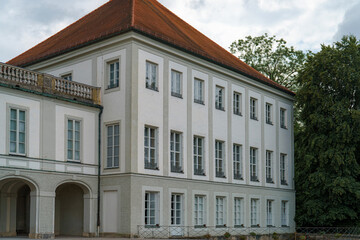 Historic building with white facade and red roof set against a cloudy sky at a serene location