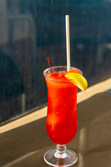 Red cocktail with cherry and lemon in the bar
