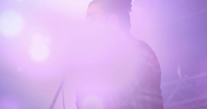 Singer holding mic concert stage activating purple pink lens flares obscuring view energizing show