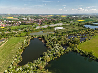 A stunning aerial view showcases lush landscapes adorned with serene lakes and expansive fields,...
